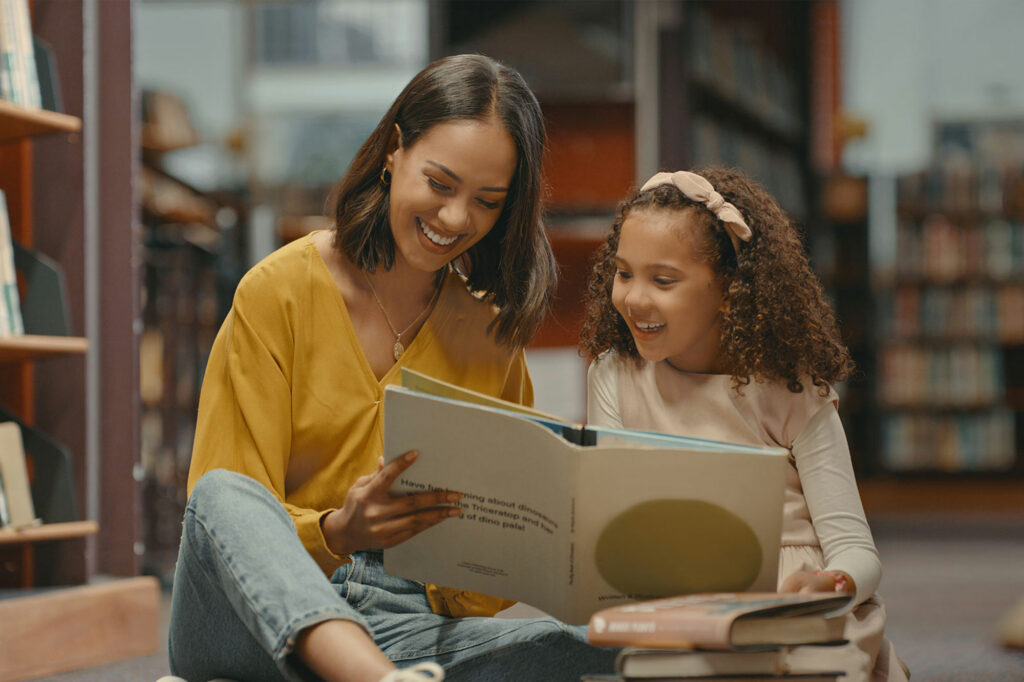 A literacy teacher encourages an elementary school girl's attempt at sounding out words