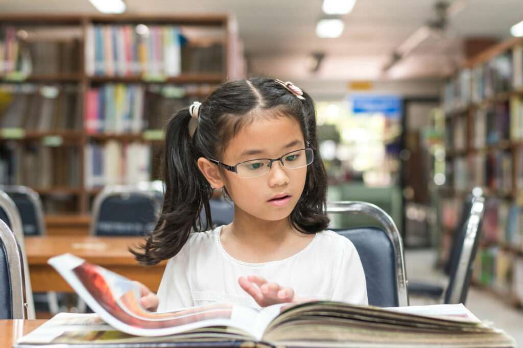 An elementary school reader in a library experiencing a book