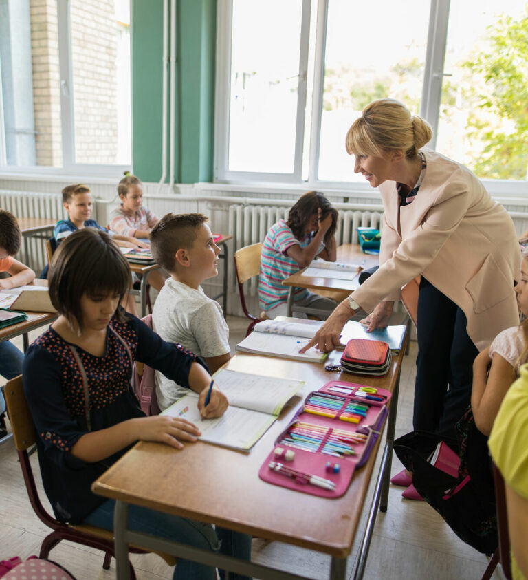 Elementary school teacher guiding a middle school boy during a literacy workbook lesson
