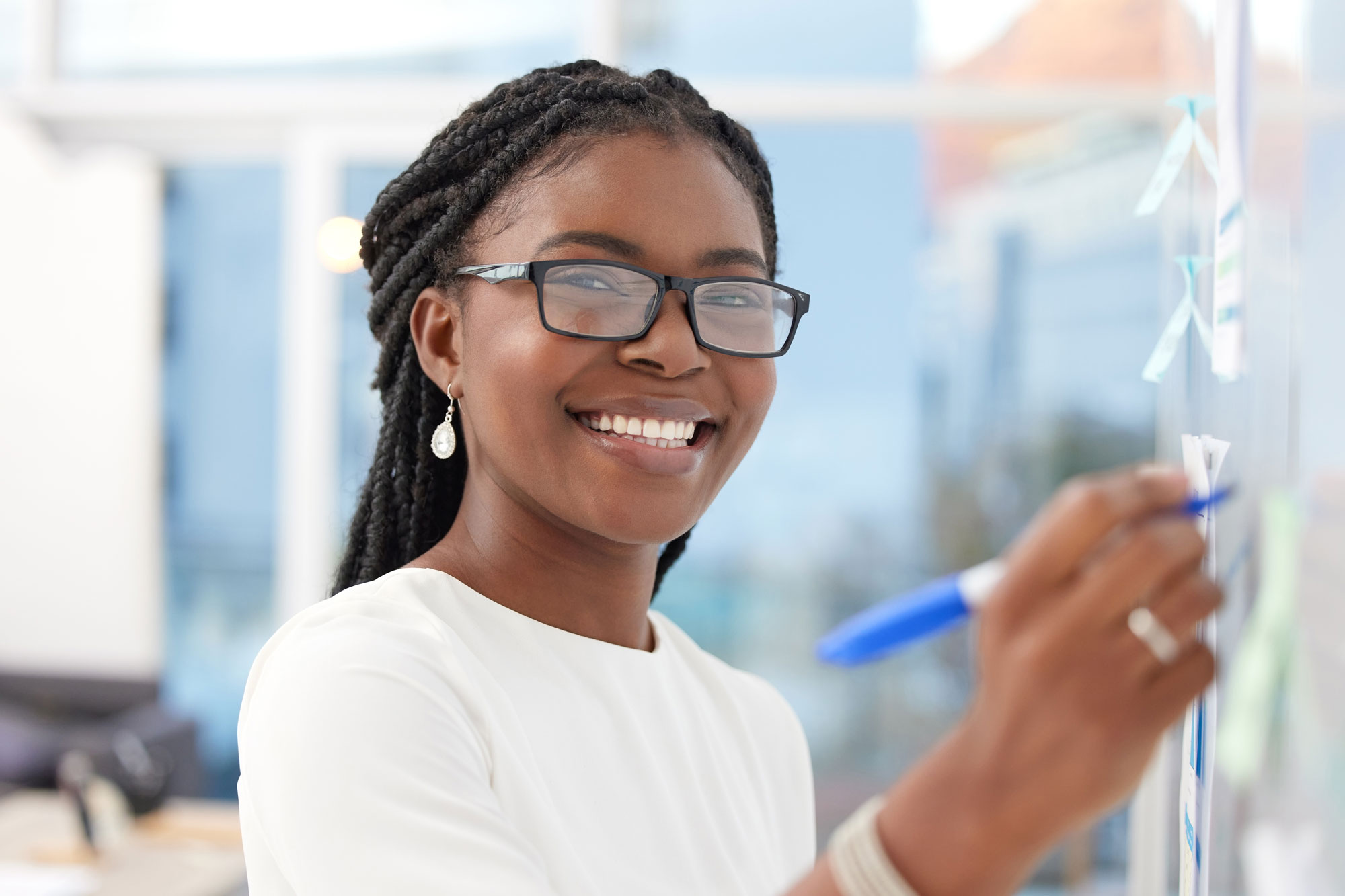 A young, smiling teacher writes on a white board