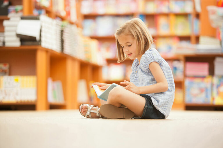 A confident elementary-school girl sounds out words in a book she chose at library time