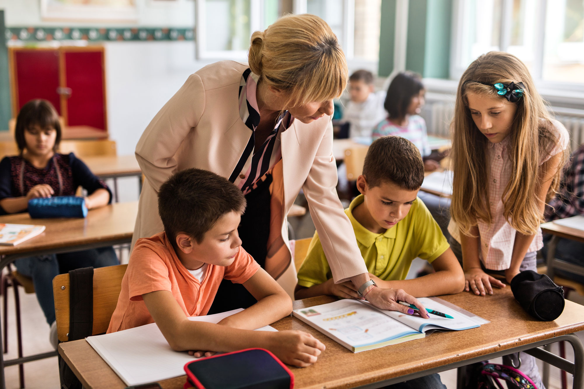 Reading teacher gives one-on-one guidance to children using phonics workbooks