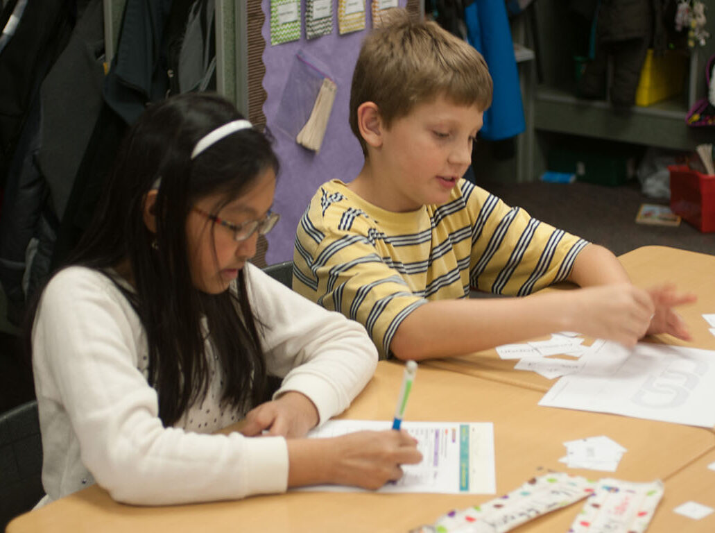 Students engaged with literacy manipulatives and phonics workbooks.