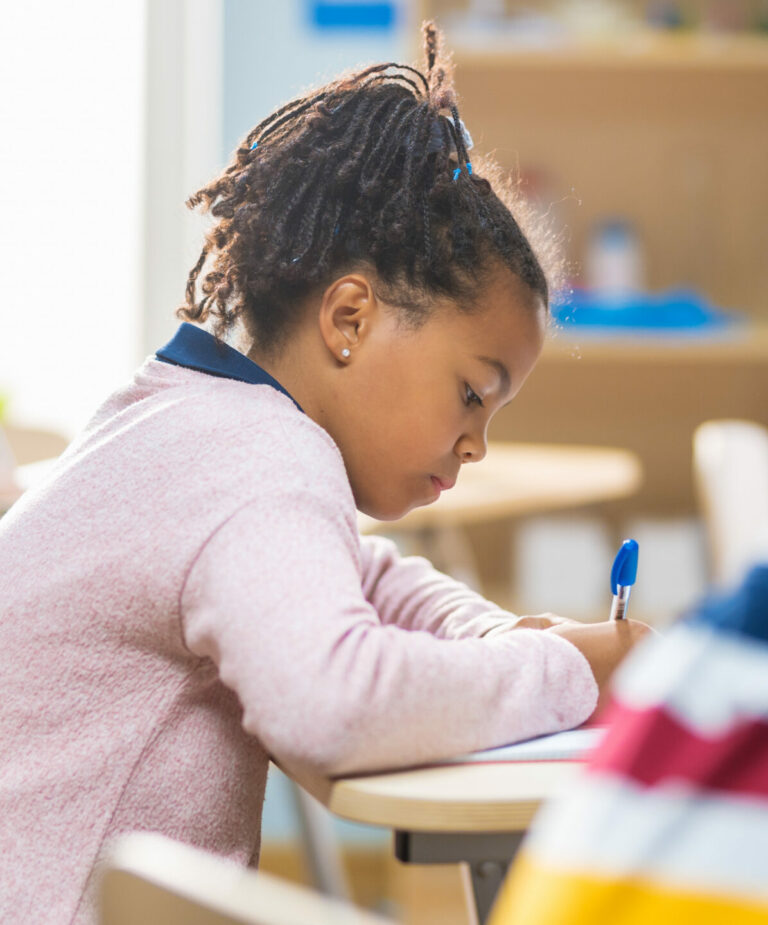 An elementary school girl absorbed in her literacy workbook lesson