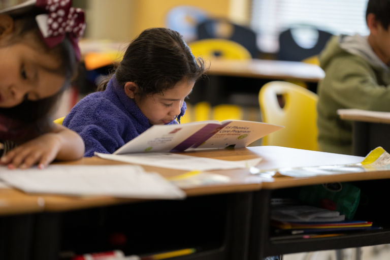 Student sitting at deck looking at a phonics core program booklet.