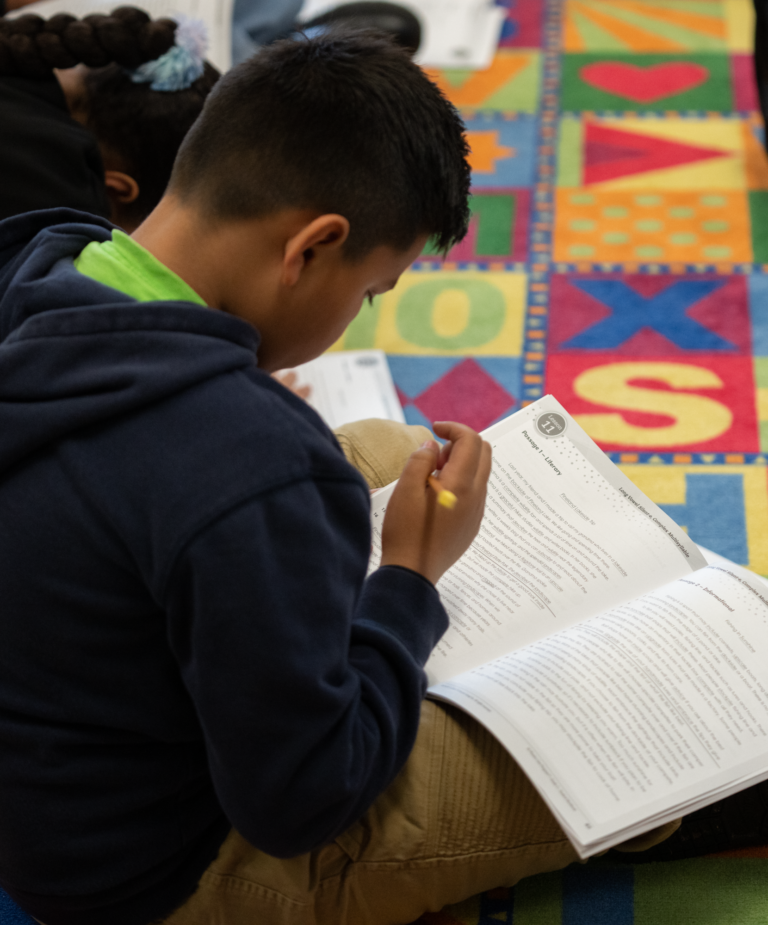 A middle school boy works in his phonics book, preparing to read harder words