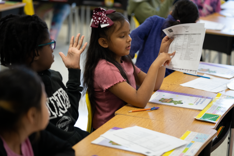 Young students looking at a phonics worksheet together in class.