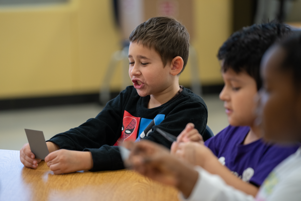 Elementary school students sound out words together while holding phonics cards