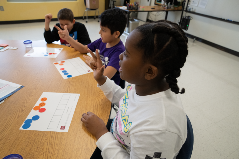 Students sitting together at a large deck with worksheets in front of them.