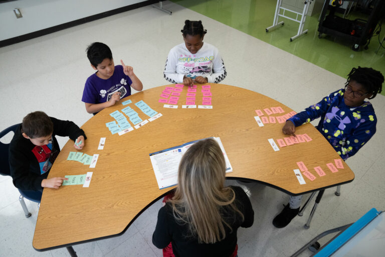 Elementary school students working with instructional manipulatives, guided by their reading specialist