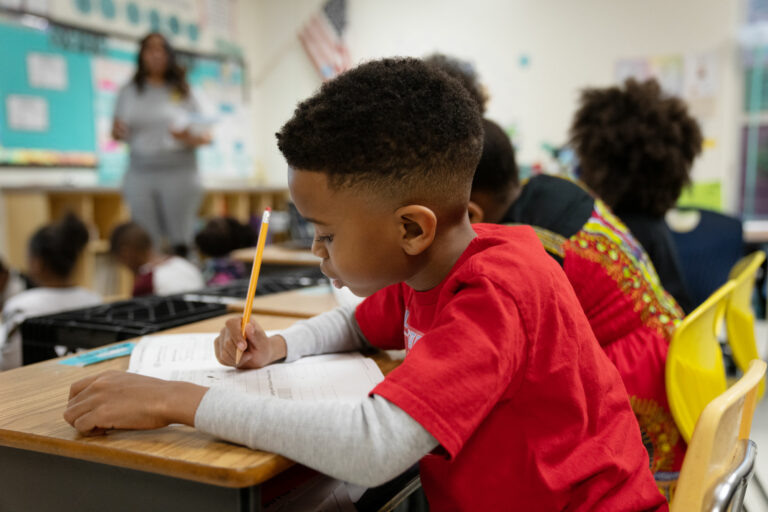 A student's hands and eyes are engaged in his phonics learning as he writes in his student workbook