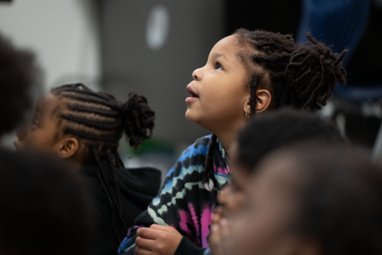 Student sitting on the floor looking up eager to learn.