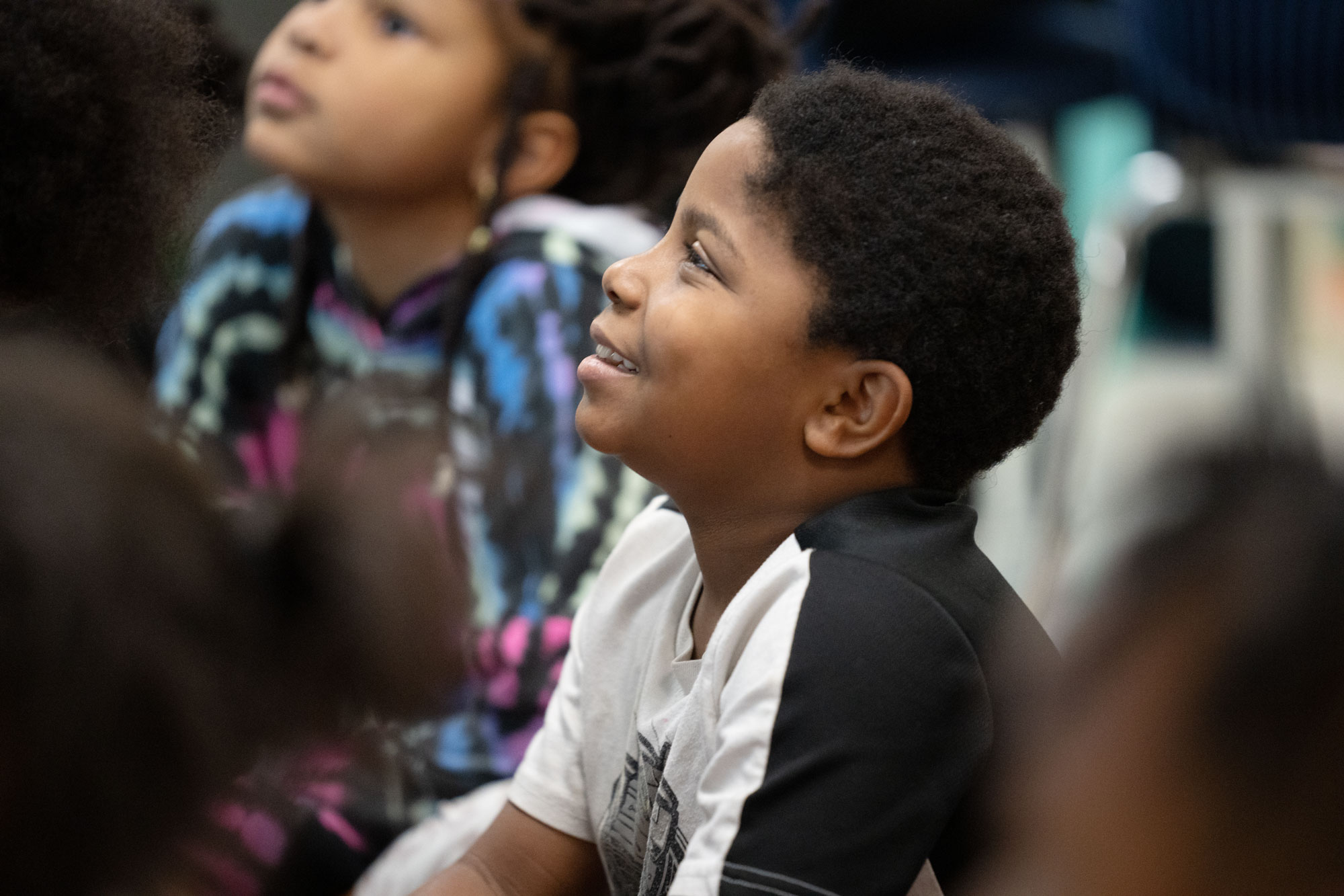 Happy elementary school students sitting on the carpet during story time