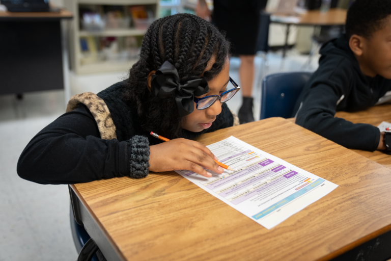 Student sitting at desk reviewing a worksheet.