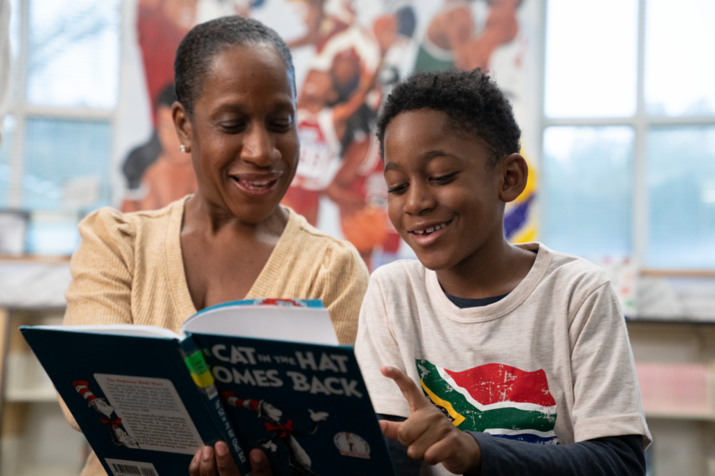 A parent guides her middle school student as he proudly reads a chapter book