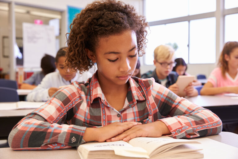 african american middle school student reads in classroom