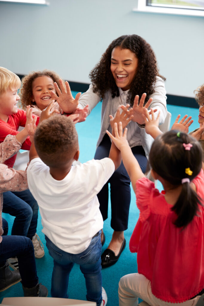 A young teacher high-fives her elementary school students