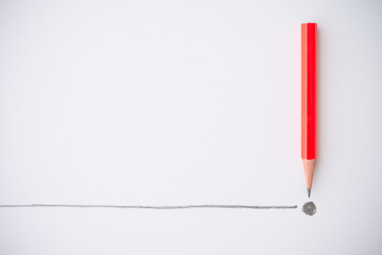 red pencil pointing to drawn line and period, representing a boundary or tipping point