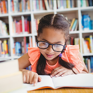 A girl proudly reads on her own, pointing out words as she decodes them