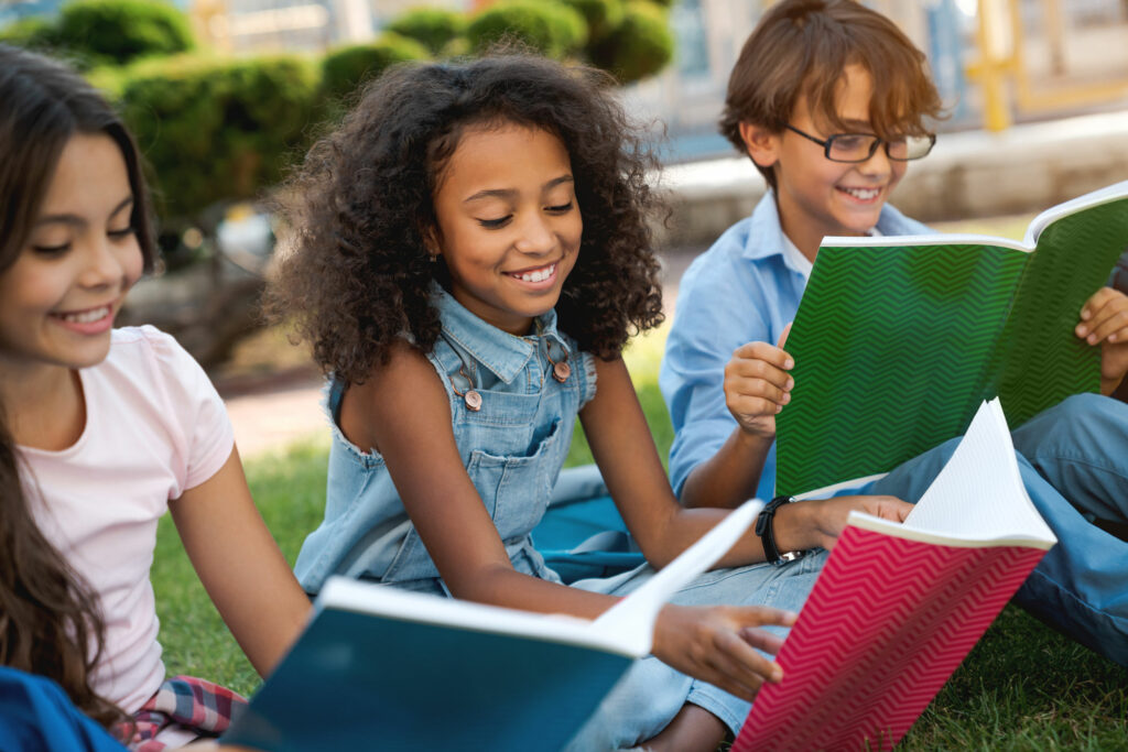 Older elementary school students enjoy an outdoor reading session