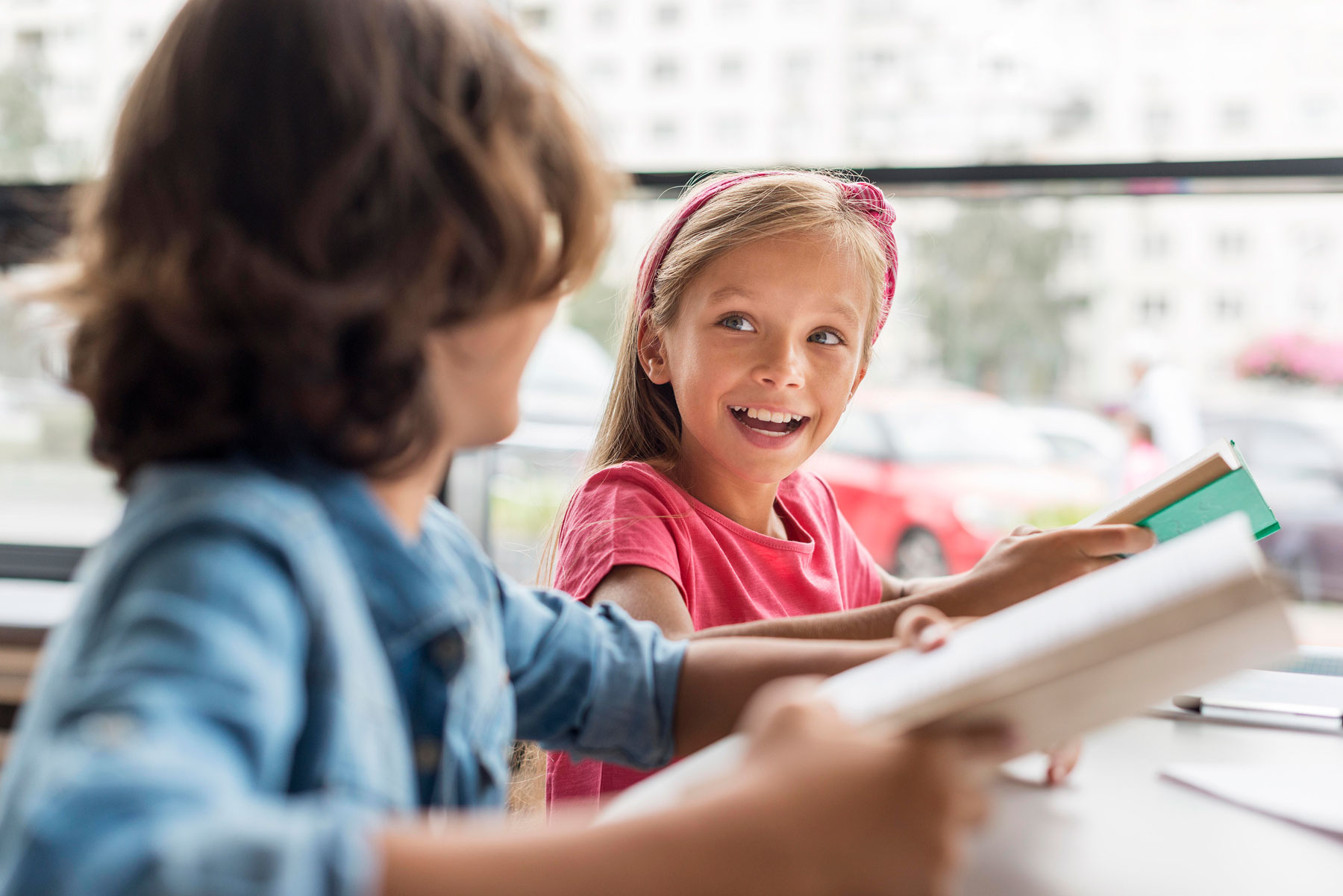 An older elementary school girl smiles at a classmate during a phonics lesson