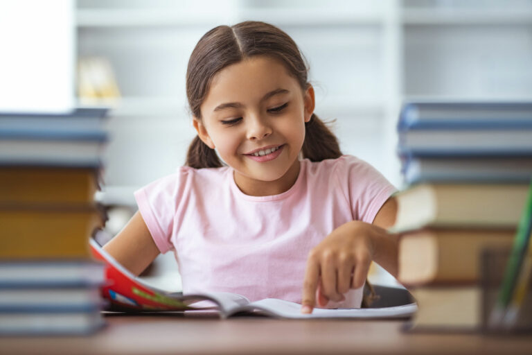 elementary student reads a phonics workbook happily in library