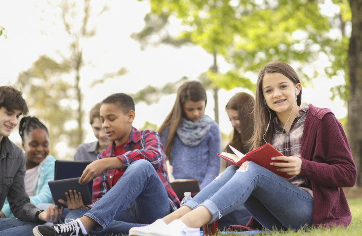 Middle school reading students discuss their books during an outdoor reading session