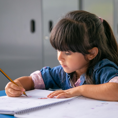 An elementary school student focuses on new words as she writes phonics responses in her workbook