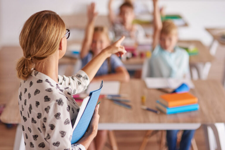 A teacher calls on students with hands raised during a phonological awareness lesson