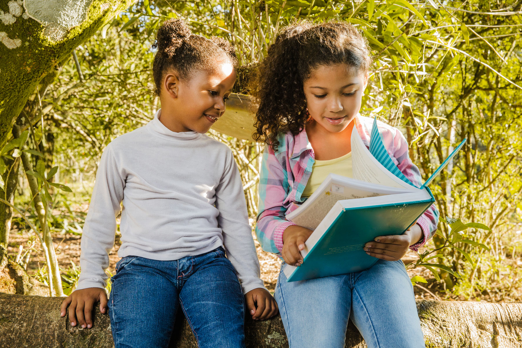 Elementary school children read a book together outside at recess