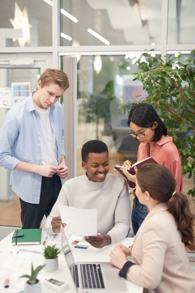 group of young, diverse professionals working together in an office, smiling and discussing webinar