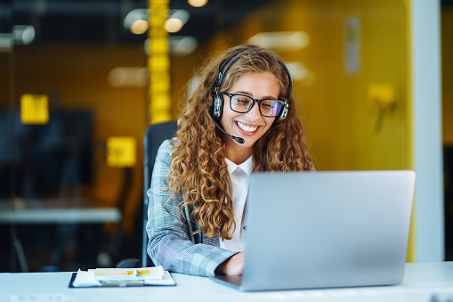 Female professional, wearing a headset, accesses 95 Percent Group Virtual Product Training with laptop from office