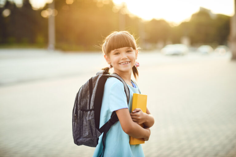 Student with backpack and book outdoors