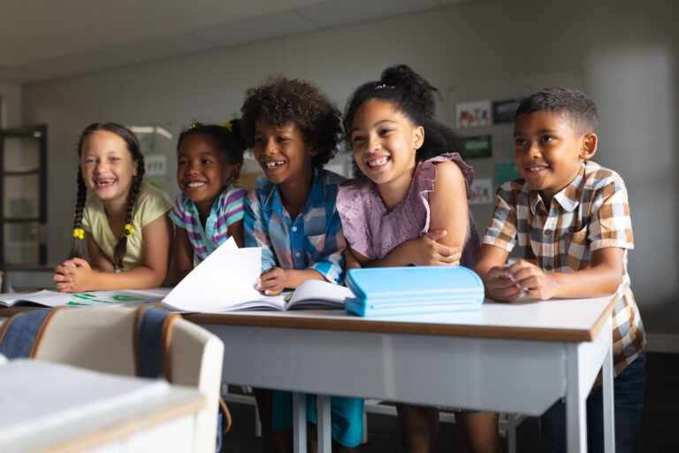 group of happy elementary students reading in their classroom