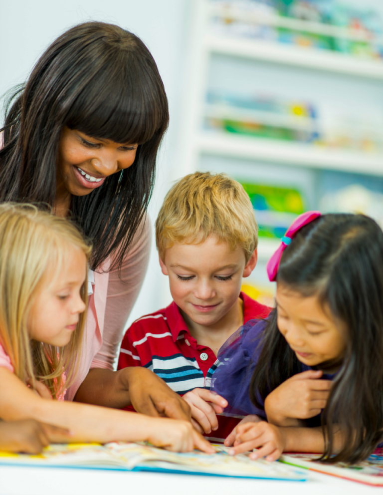 A group of children engaging in a learning activity with books, in a colorful classroom setting.