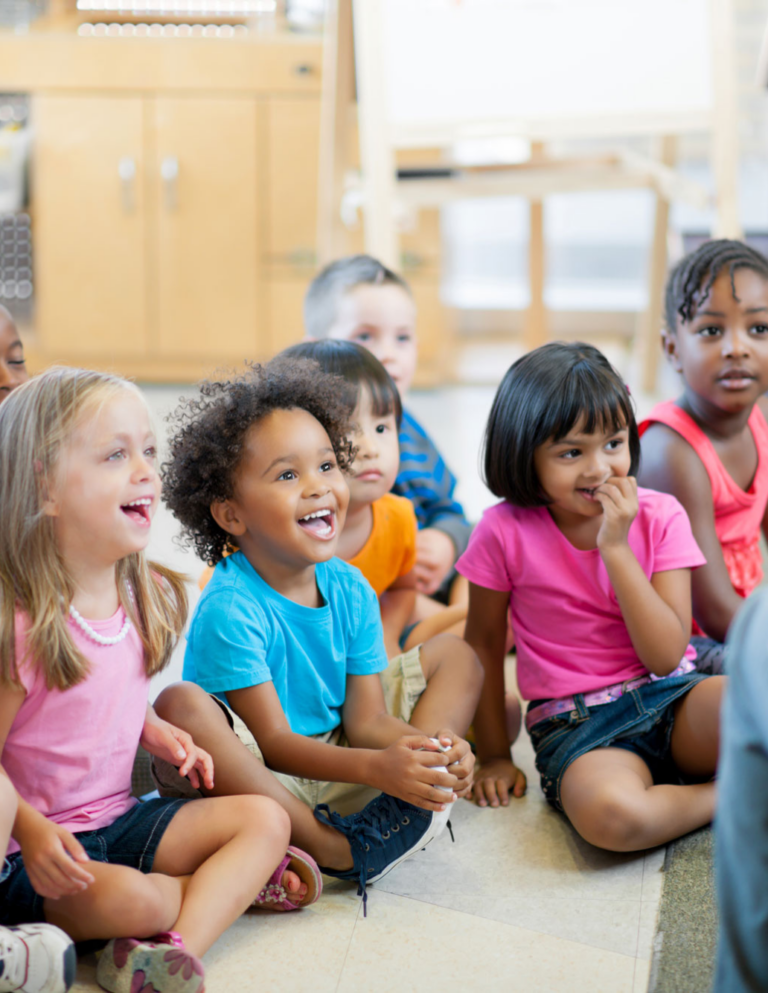 Group of diverse children sitting and smiling in a classroom