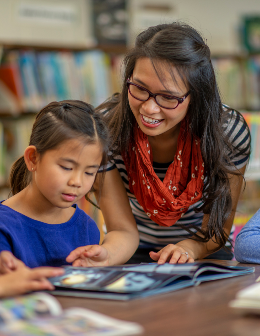 Teacher and child engaged in reading a book together