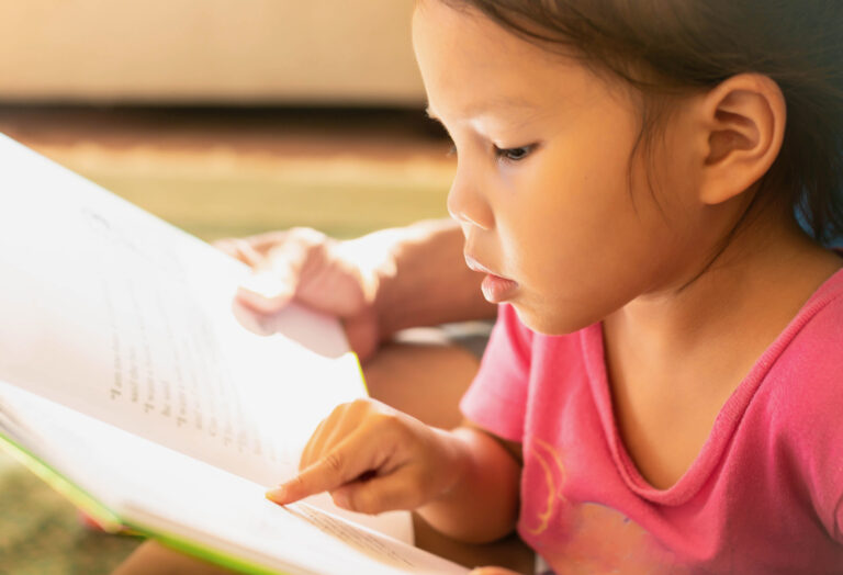 Student intently reading a book, pointing to the text