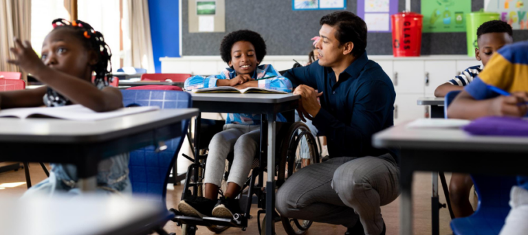 male elementary teacher helping student with literacy lesson in class