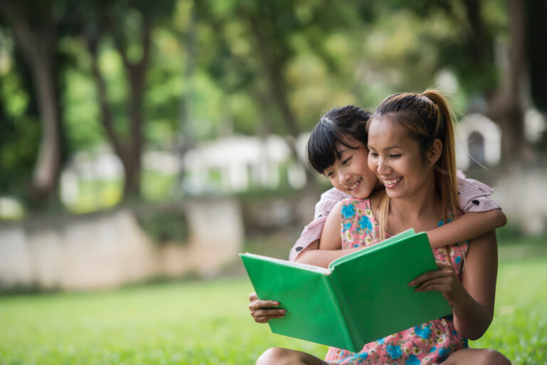 mother and daughter reading in the park together