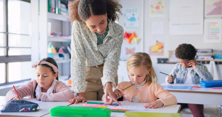 African American teacher helping her elementary school students