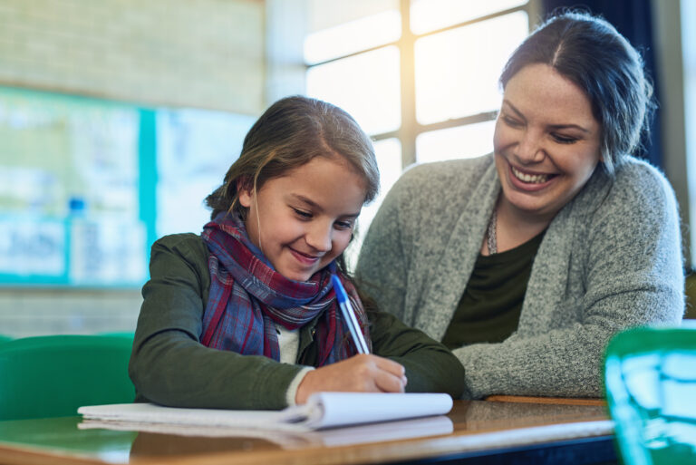 teacher happily helping student with literacy lesson