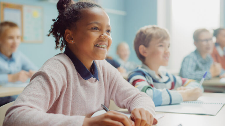 elementary school student smiling and engaged in classroom lesson