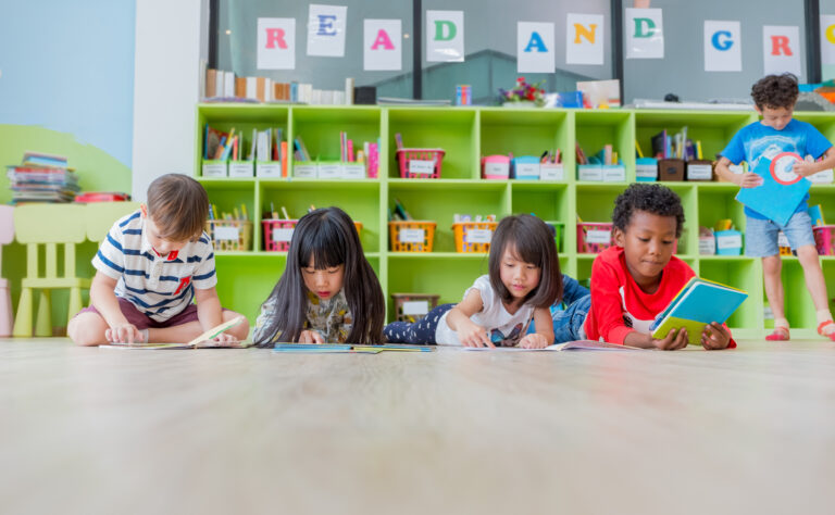 Group of diversity kid lay down on floor and reading tale book in preschool library