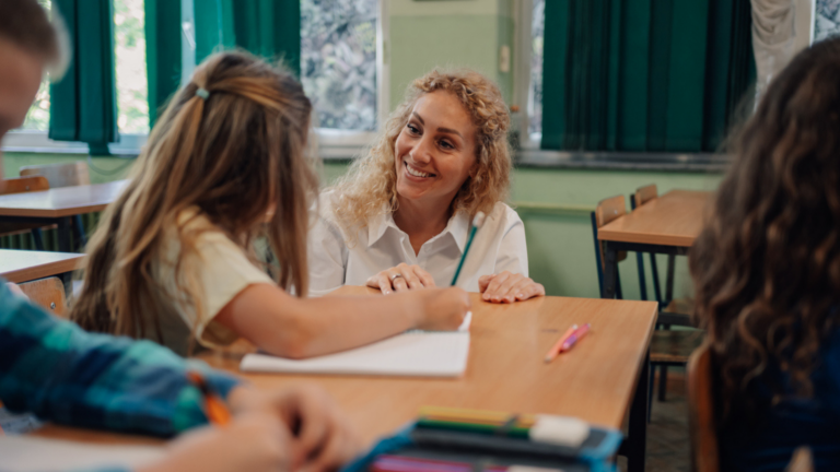 Teacher helping young girl with her studies in classroom