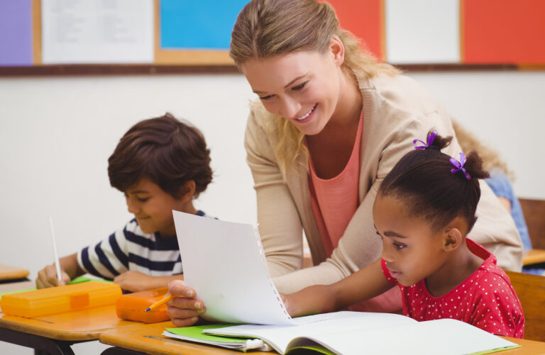 teacher helping pupil in classroom at the elementary school