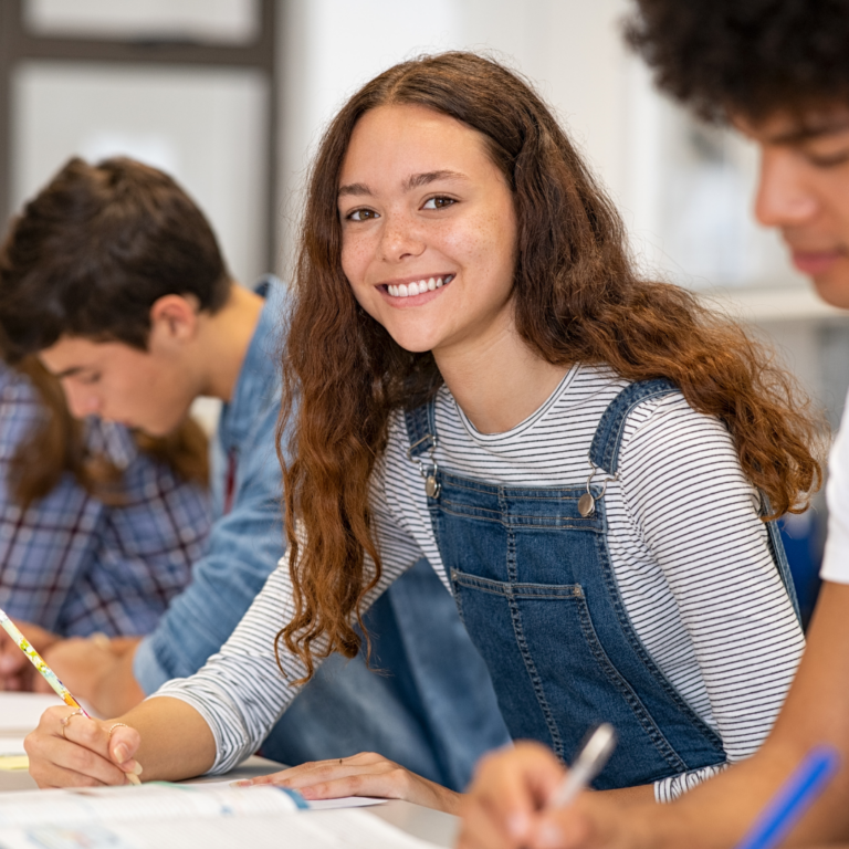 happy teen writing in class