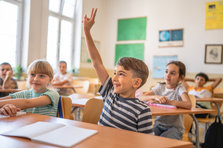 Smile school boy raise hand to answer the teacher question